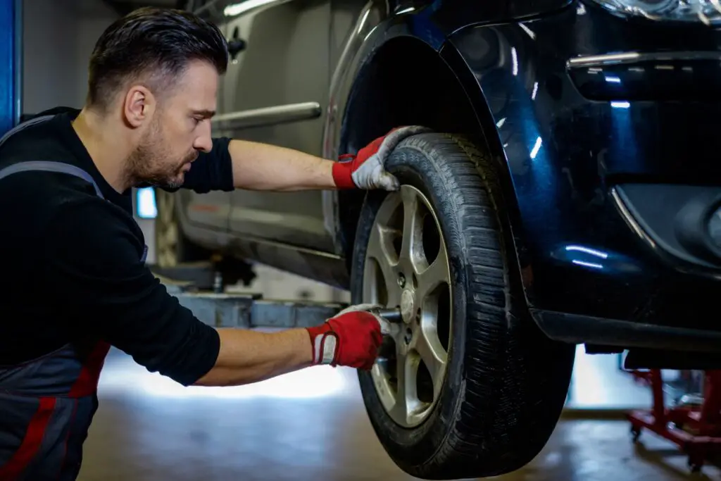 A mechanic quickly changing a car tire on a jack stand.