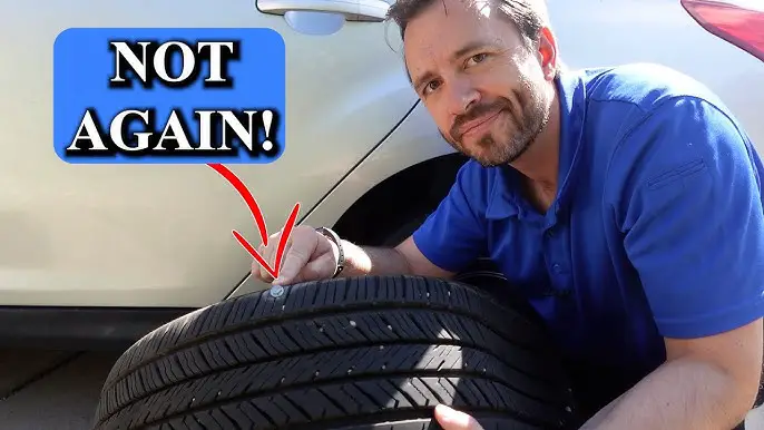 A person inspecting a flat tire on the side of a road.